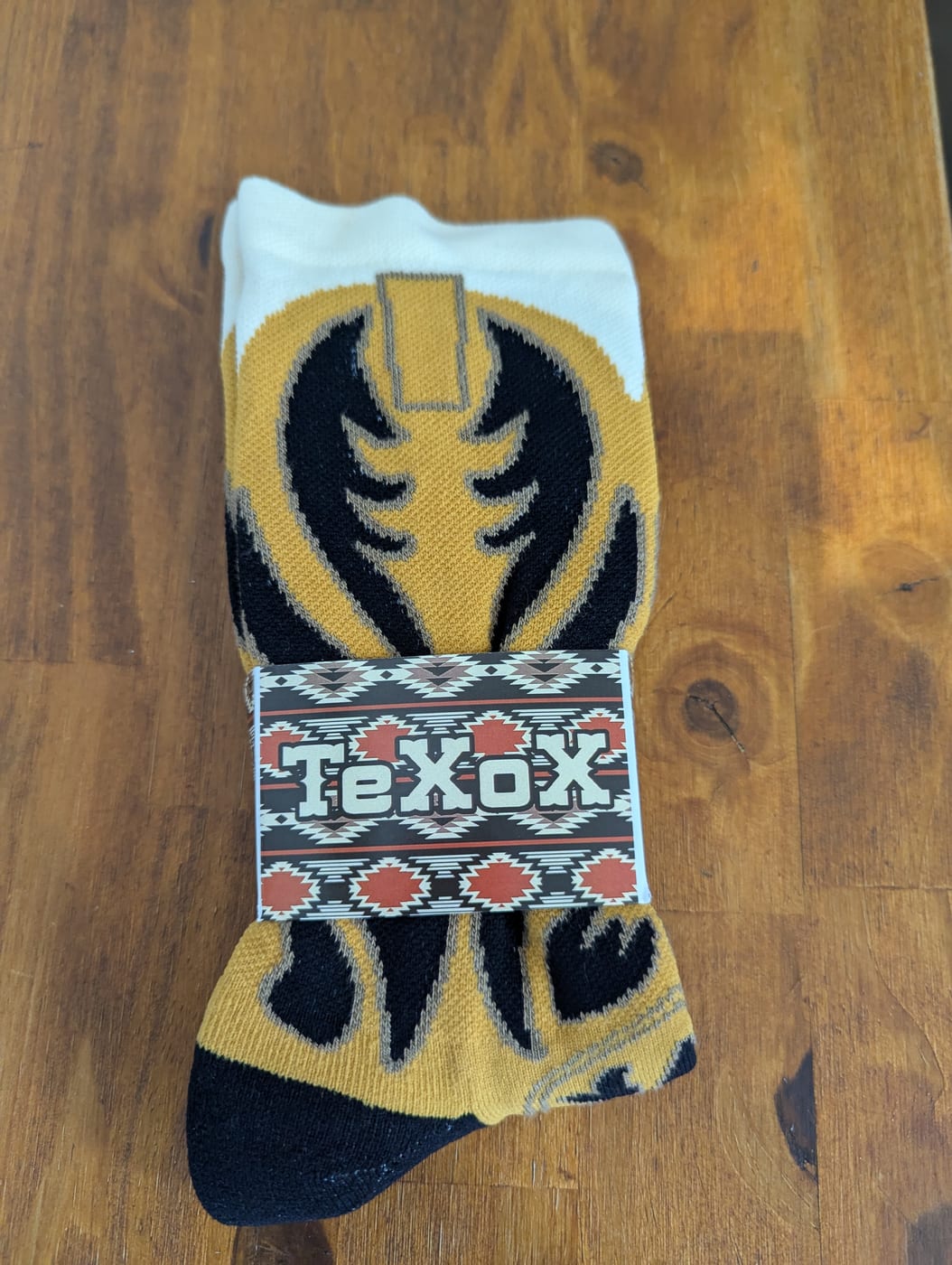 A folded pair of cowboy boot socks with the printed western band wrapped around them, ready for a counter.
